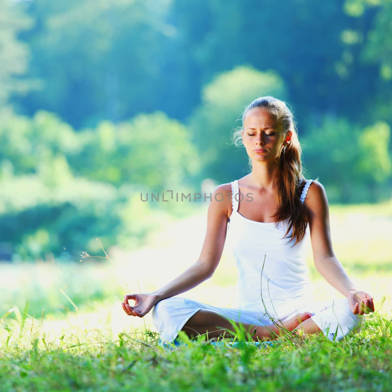 Young woman doing yoga exercise in green park