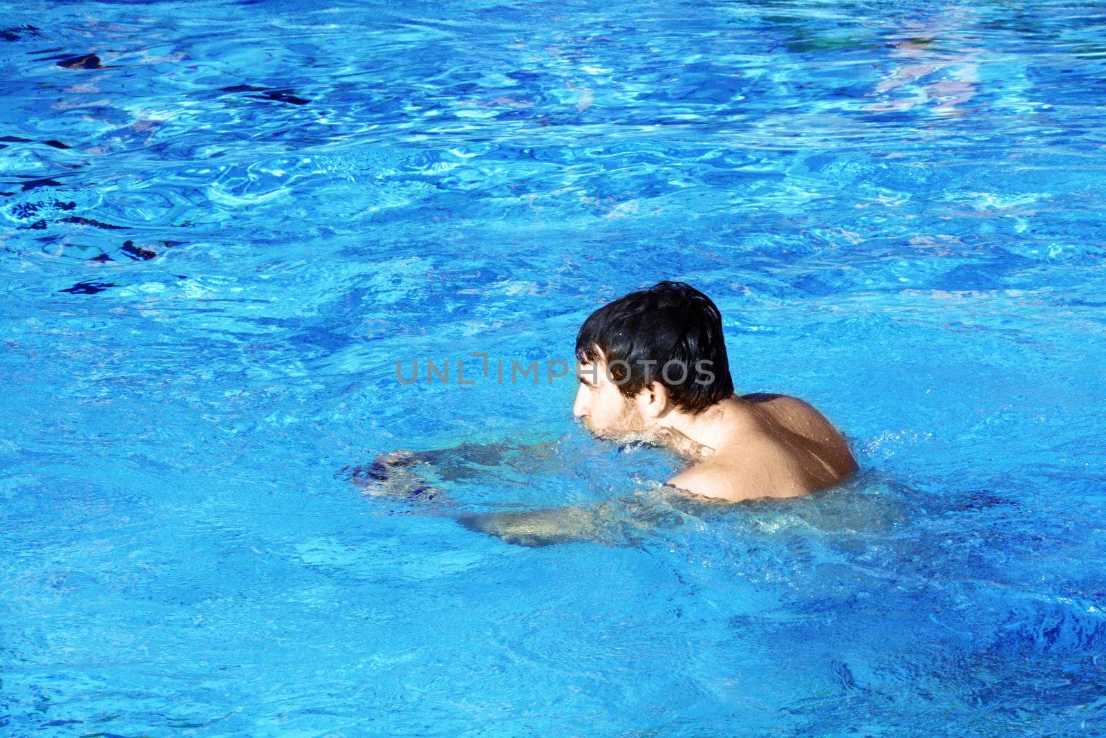 young swimmer in blue water by photochecker
