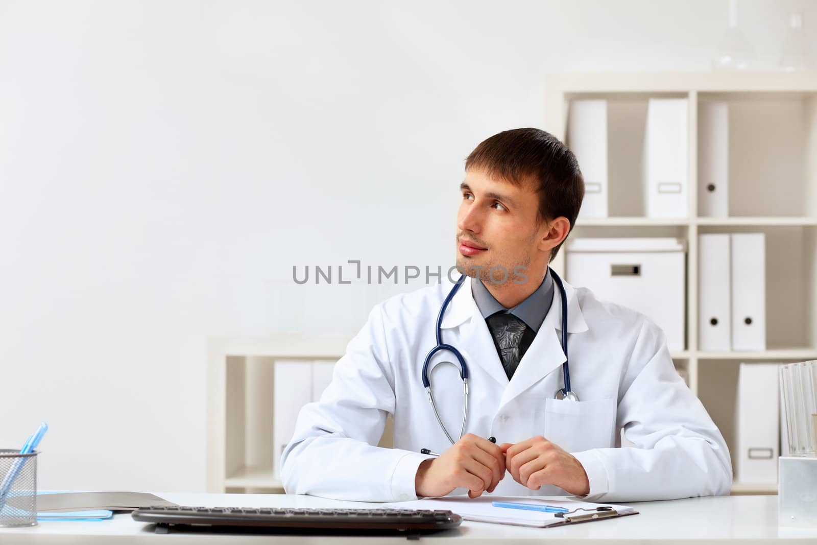 Young male doctor in white uniform at workplace