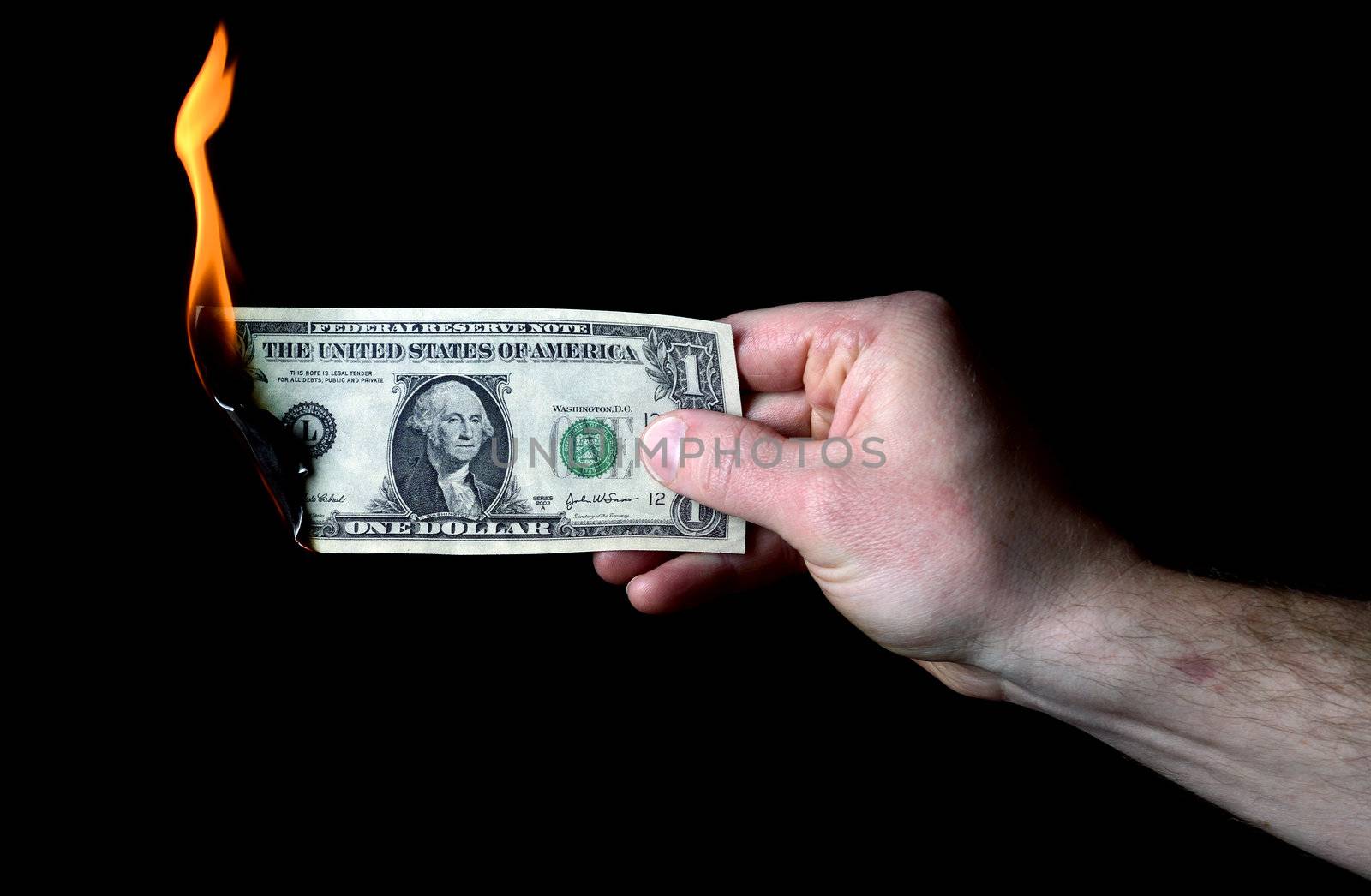 hand holding burning dollar isolated on black, concept of money to burn