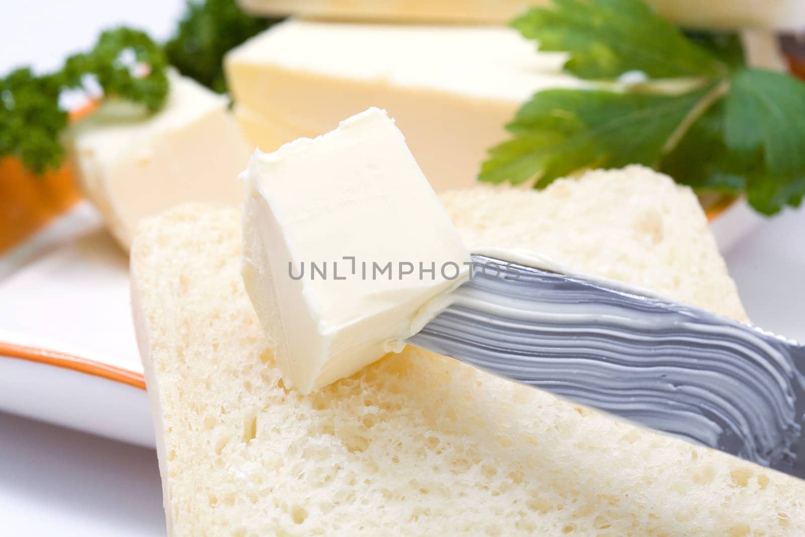 Stock photo: an image of fresh butter on a knife with bread and parsley