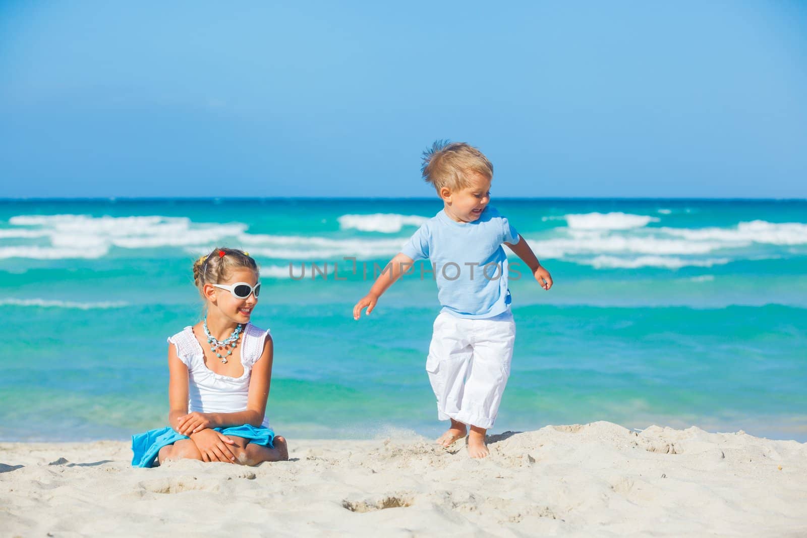 Young girl and boy playing happily at pretty beach by maxoliki