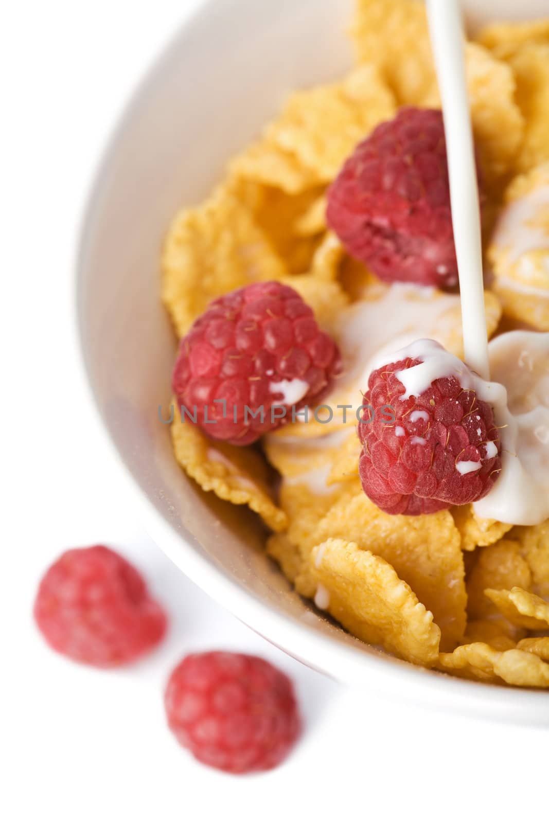milk pouring into bowl with muesli and raspberry isolated