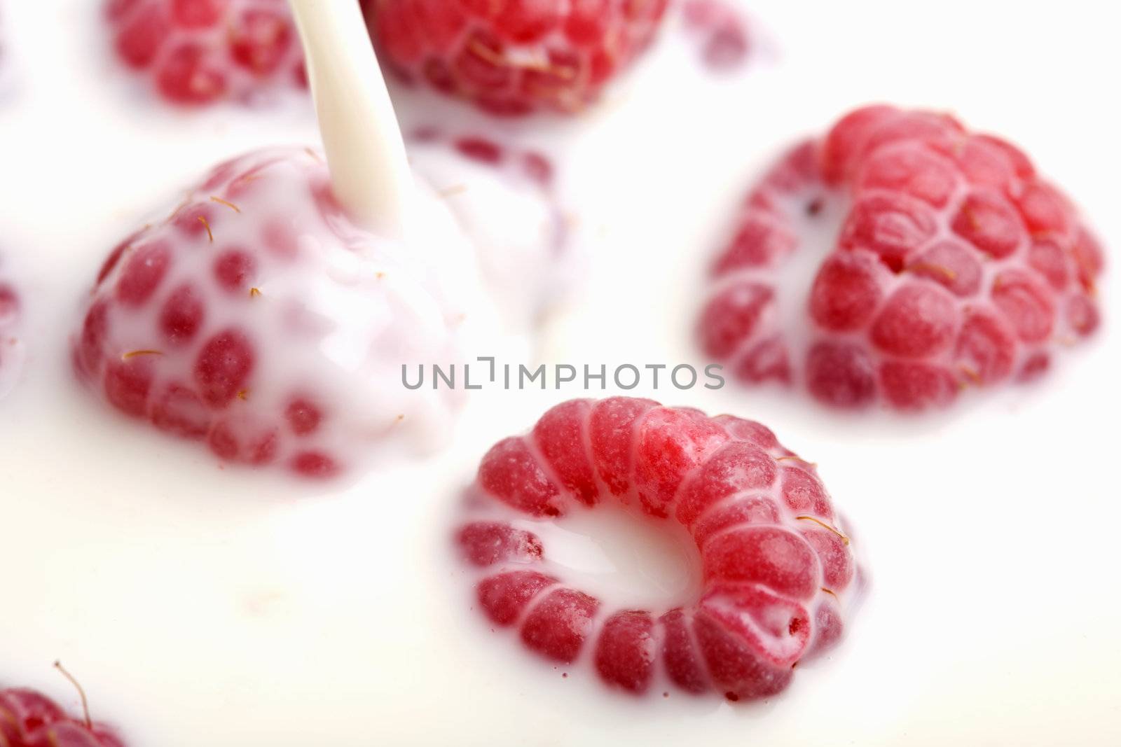 milk pouring onto fresh raspberries