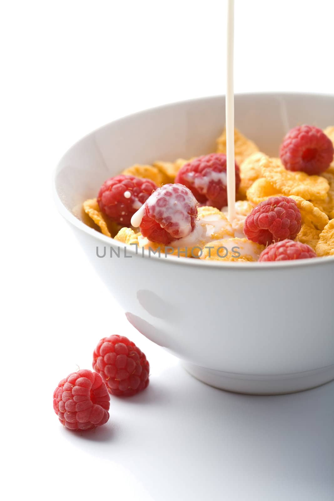 milk pouring onto muesli with raspberry isolated