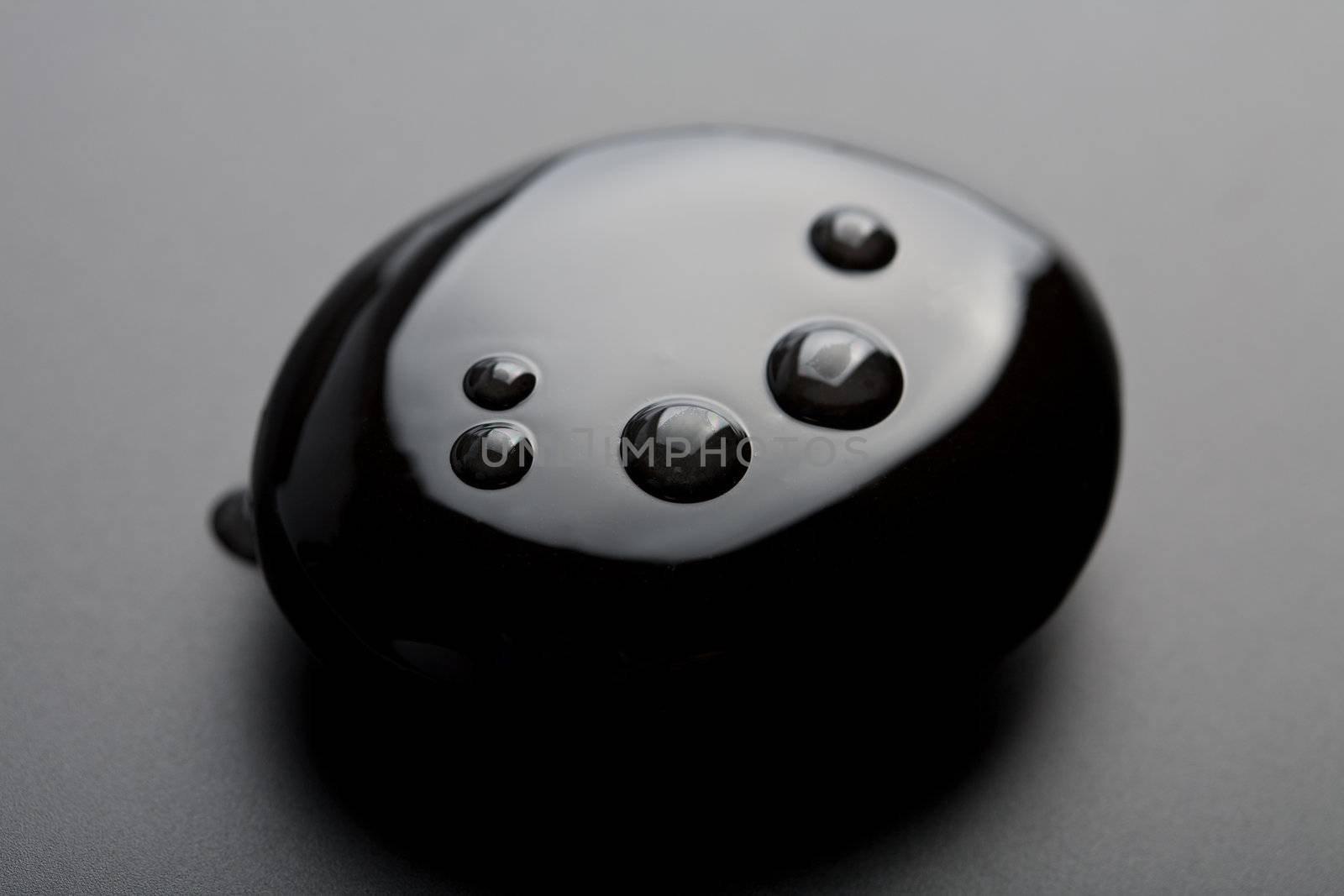 black shiny zen stone with water drops over black background