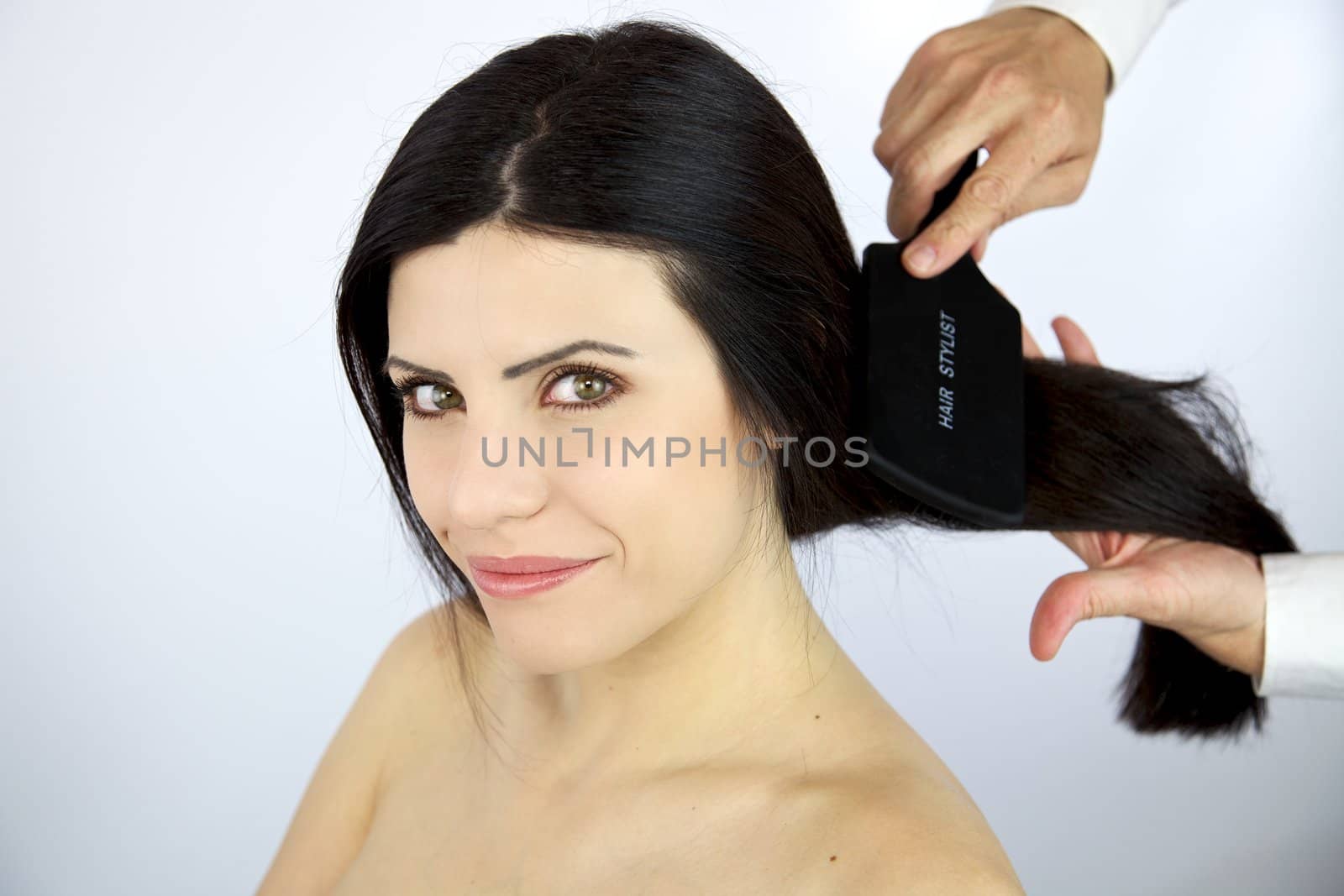 Hairdresser brushing long black hair of sexy female model