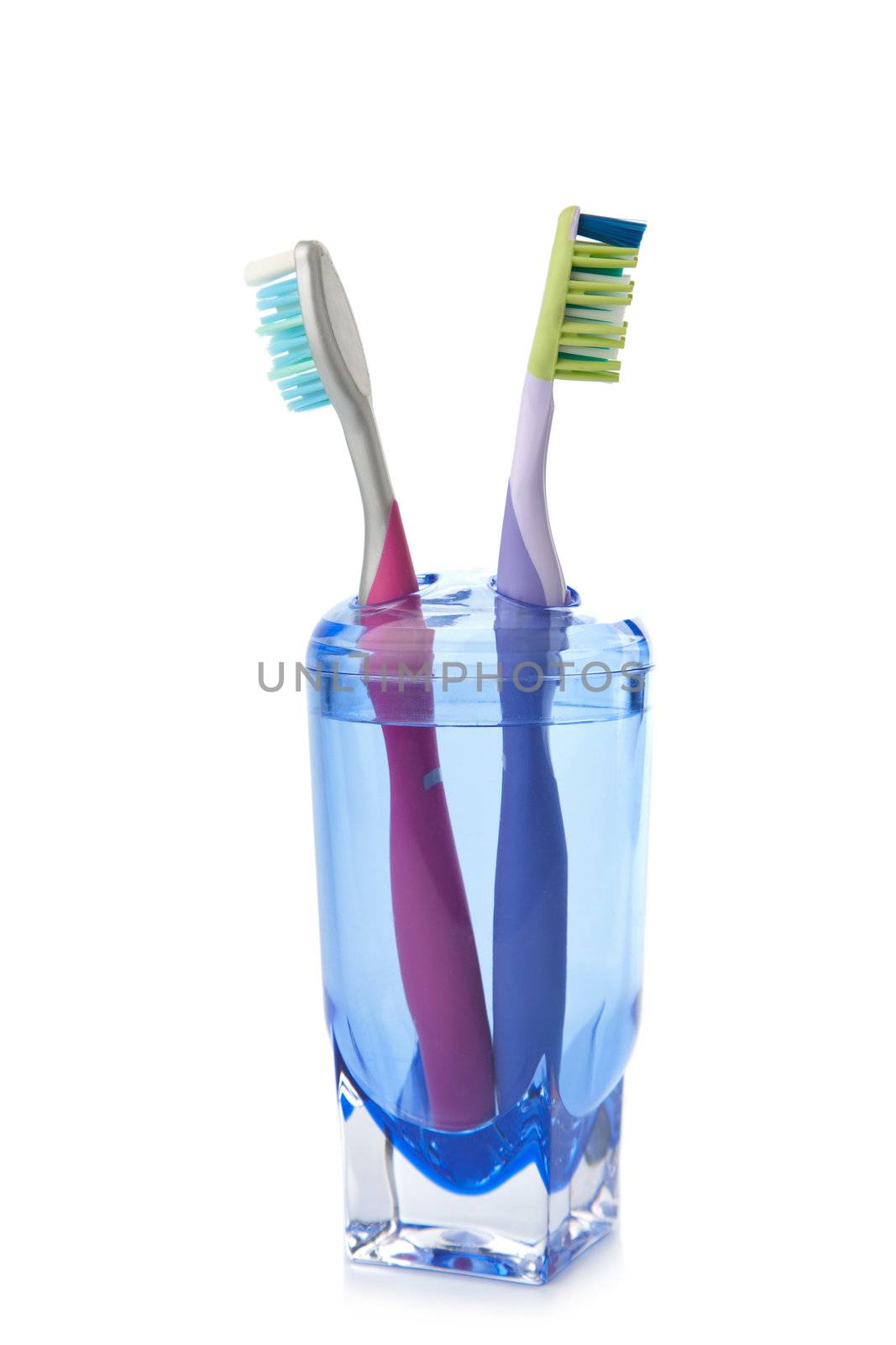 two colorful toothbrushes in glass isolated