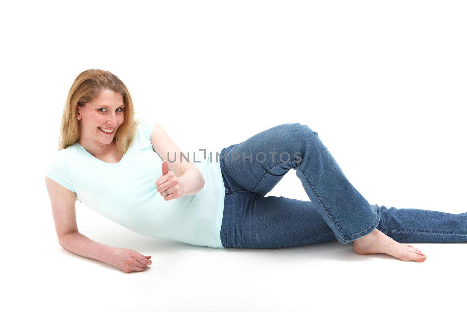 Pretty smiling blonde girl reclining on the floor showing an object in her hand