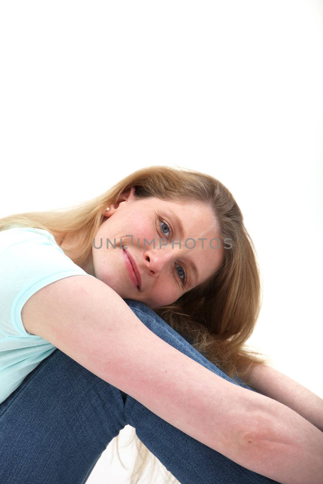 Close view of pretty smiling blonde girl with her head on her knees