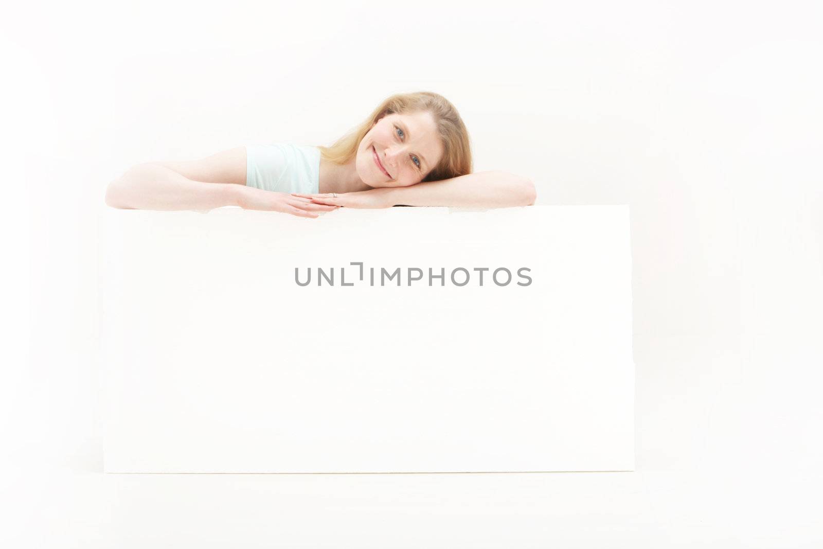 Pretty blonde girl smiling and looking very self assured over a white poster board with blank space for your message
