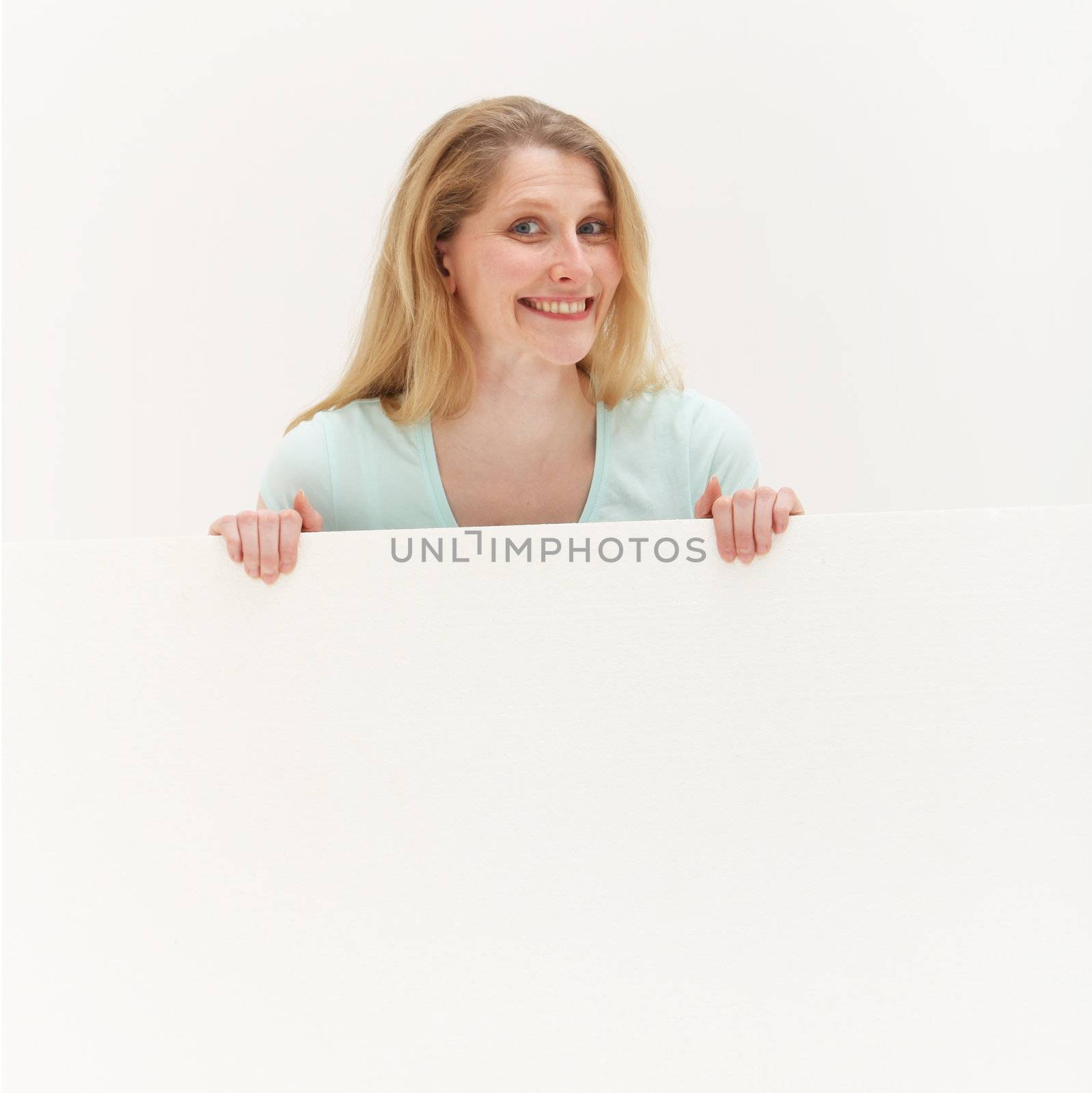 Studio shot of smiling woman behind blank white board on white background