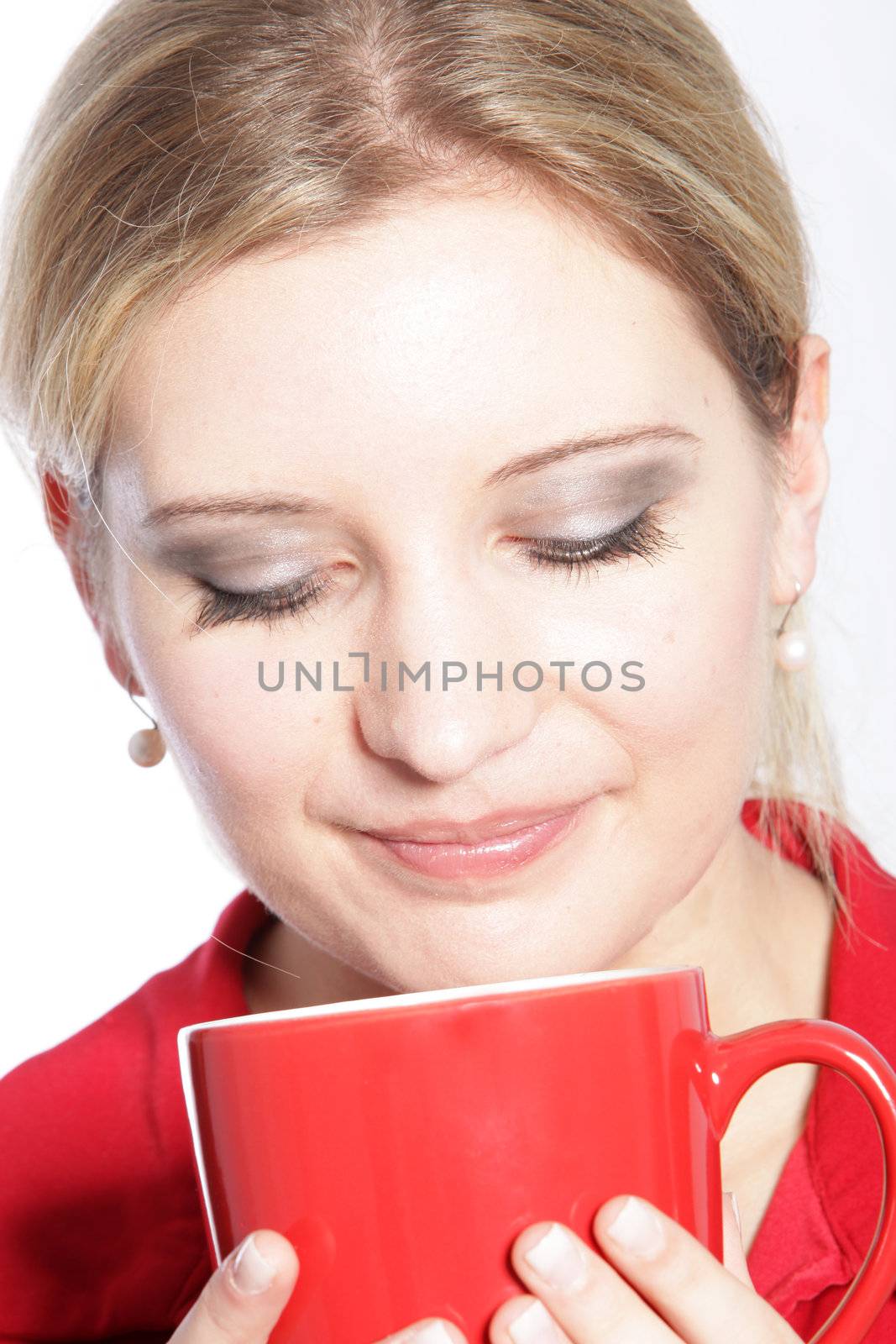 Attractive young blonde woman enjoying a mug of coffee smelling the aroma with her eyes closed in bliss