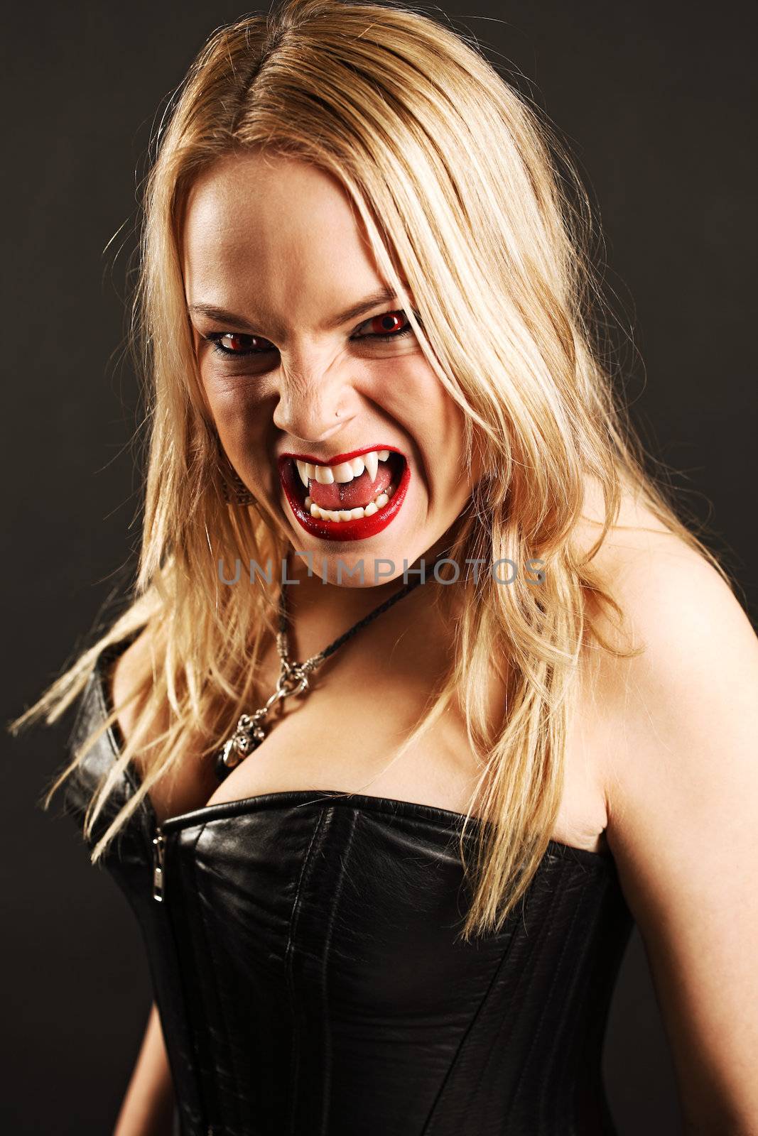 Photo of a female vampire with mouth open and fangs showing.  Harsh lighting and shadows for scarier feel.