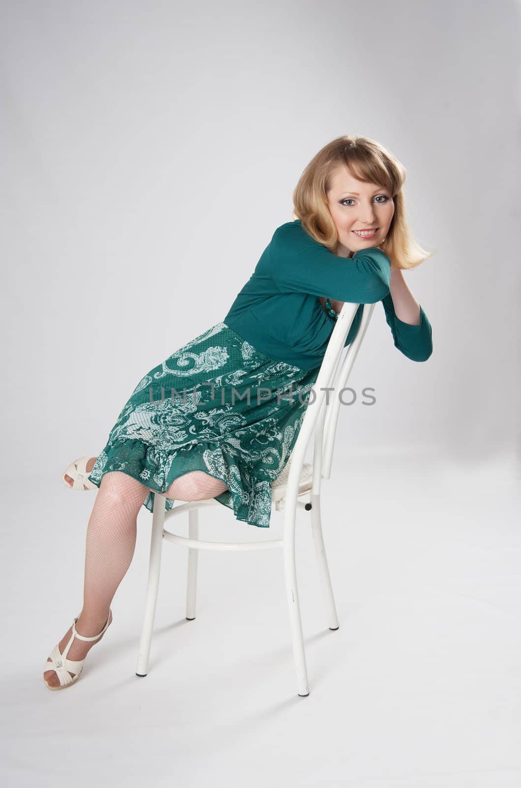 beautiful woman in a green dress sitting on a chair