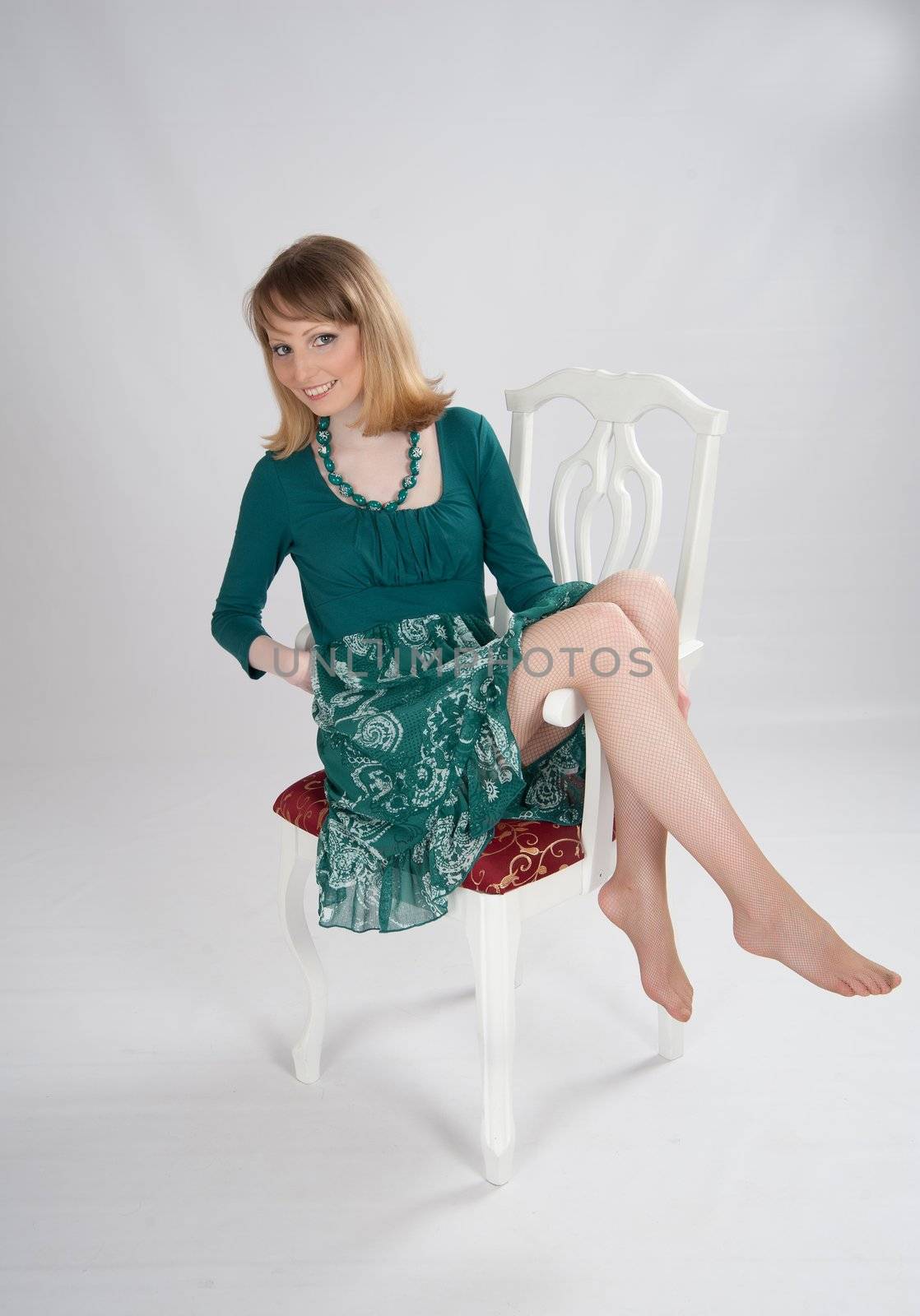 beautiful woman in a green dress sitting on a chair