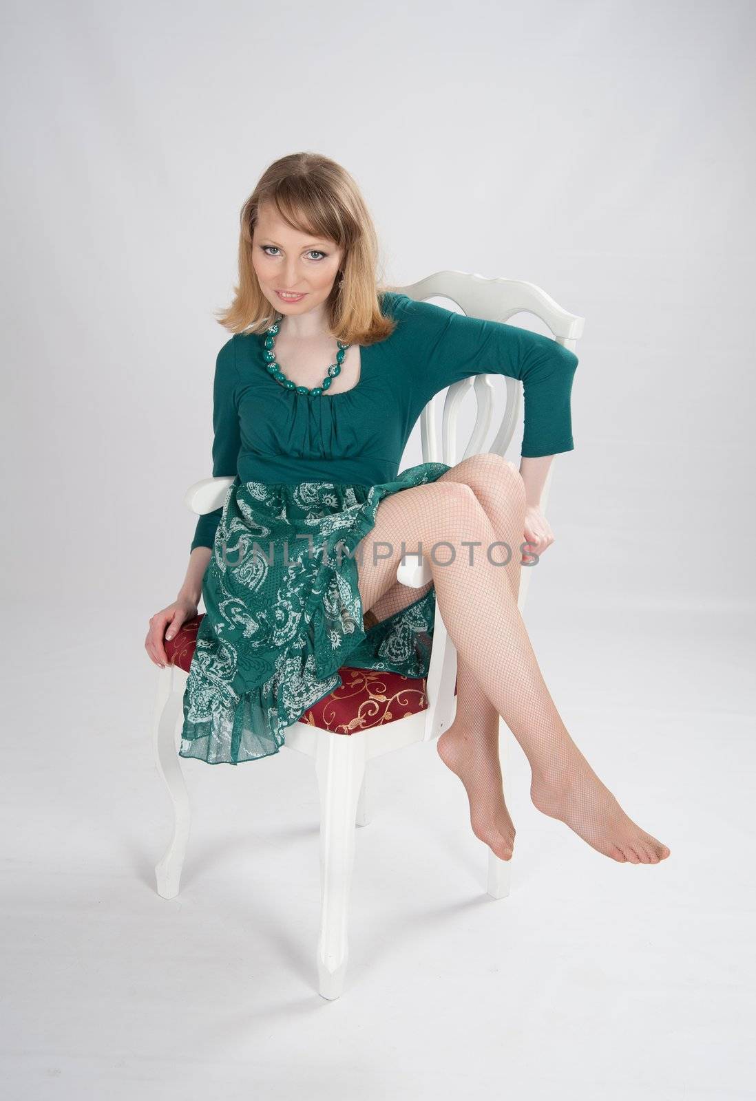 beautiful woman in a green dress sitting on a chair