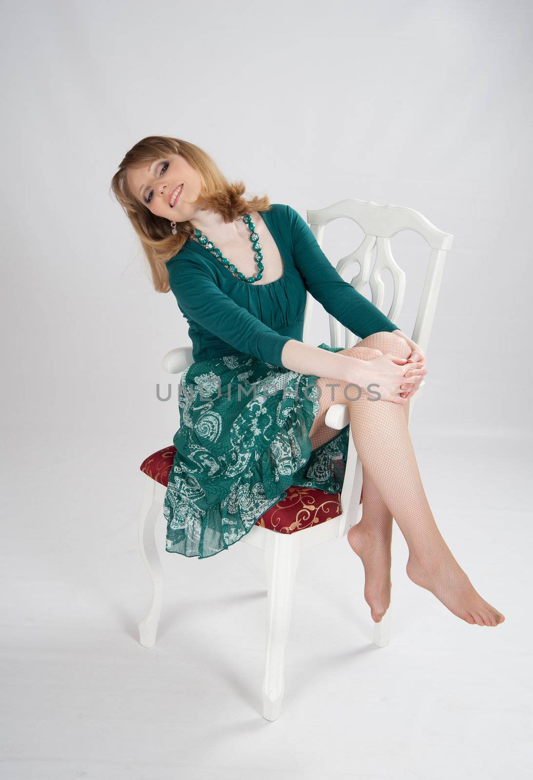 beautiful woman in a green dress sitting on a chair