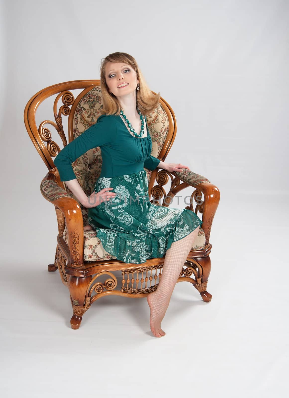 beautiful woman in a green dress sitting on a chair