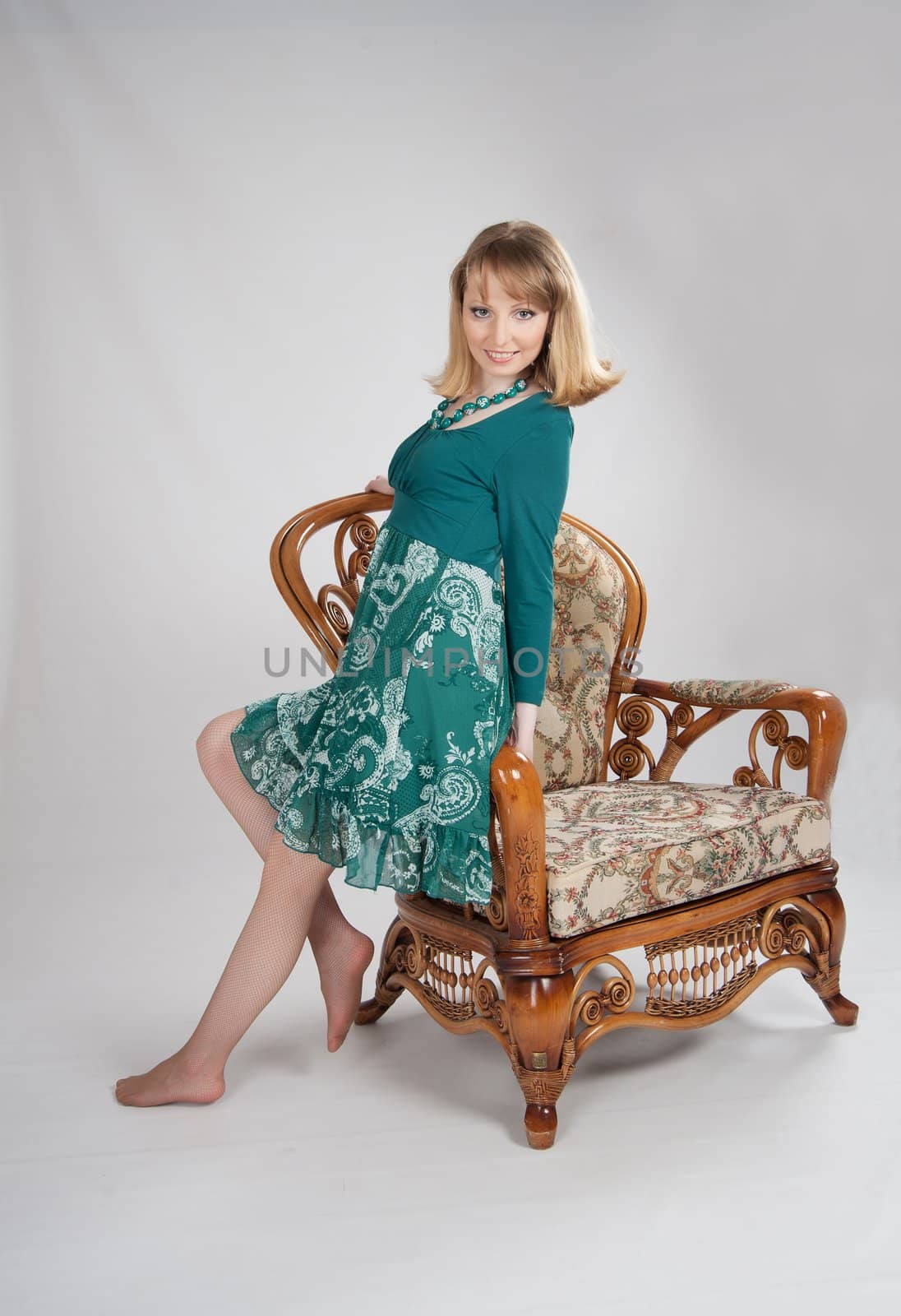 beautiful woman in a green dress sitting on a chair