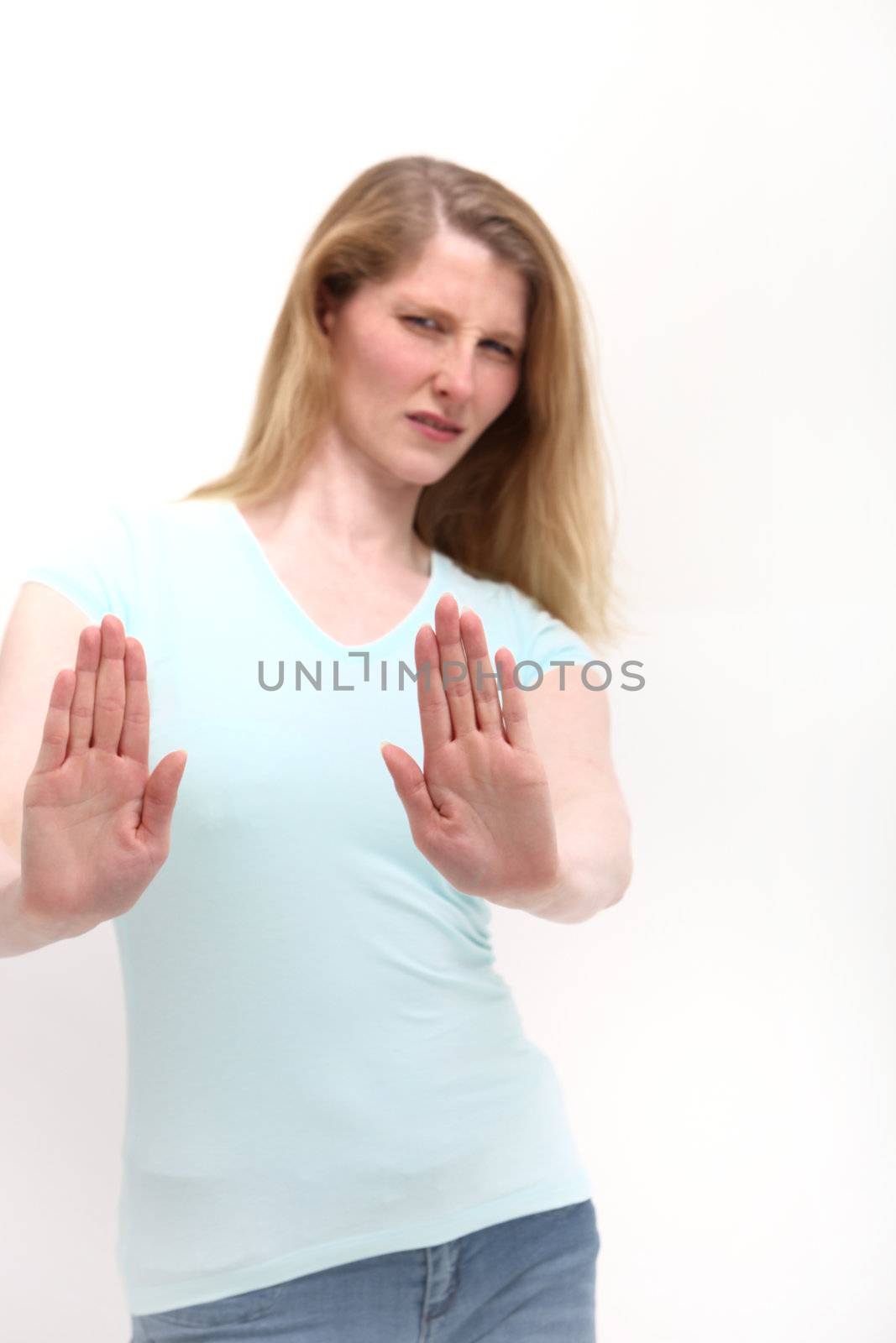 Apprehensive scared woman backing off and raising her hands to Keep Away and leave her alone when faced with mental or physical abuse