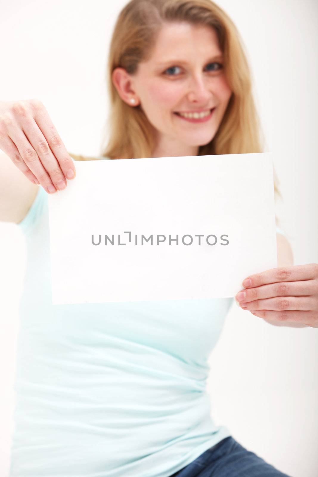 Happy girl holding blank paper at arms length. Place your message or text on the paper