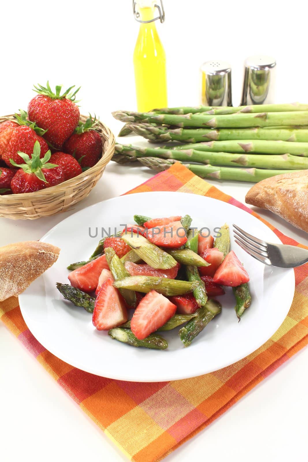 green Asparagus salad with red strawberries and bread on a light background