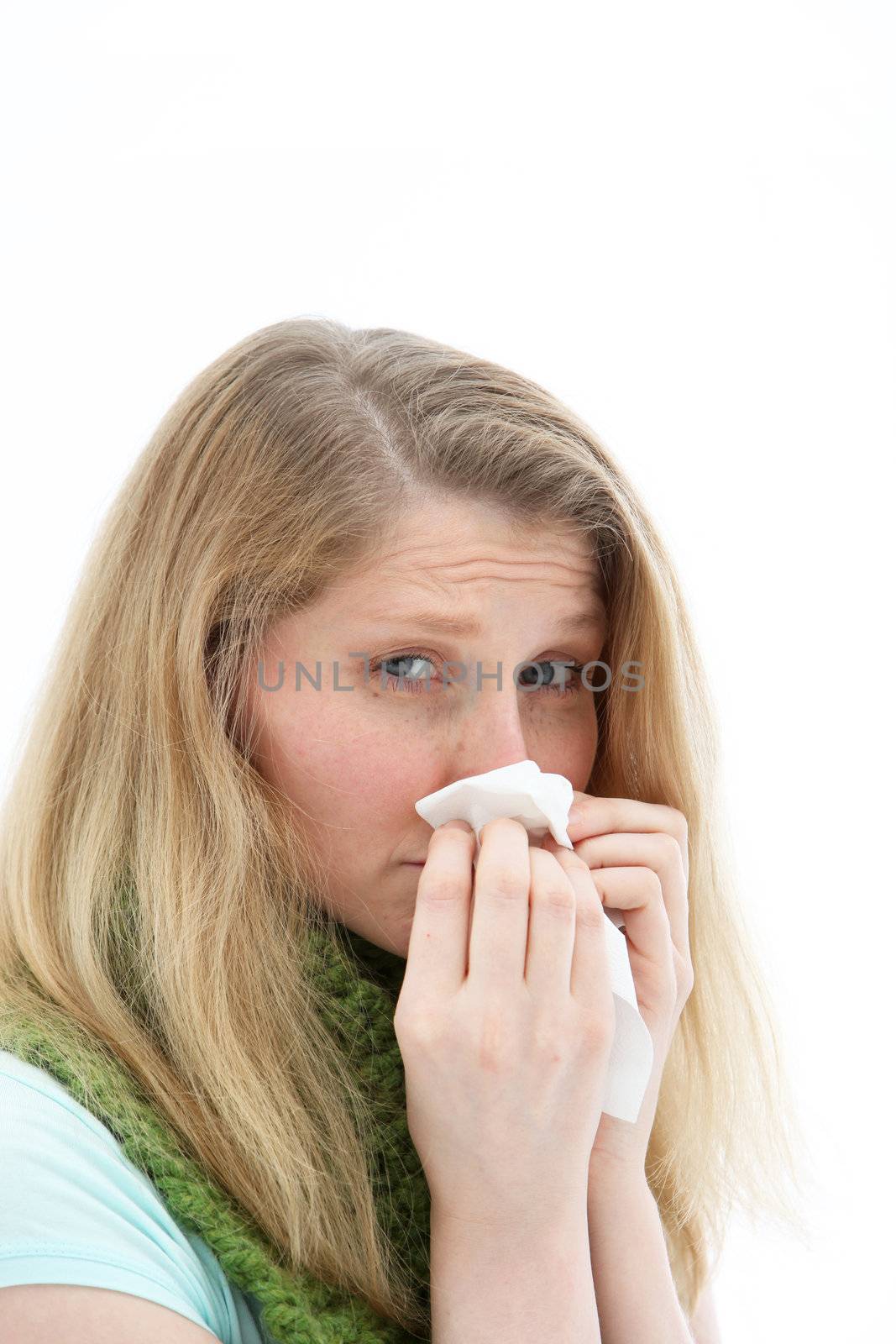 Sick woman with a dose of flu blowing her nose on a disposable tissue