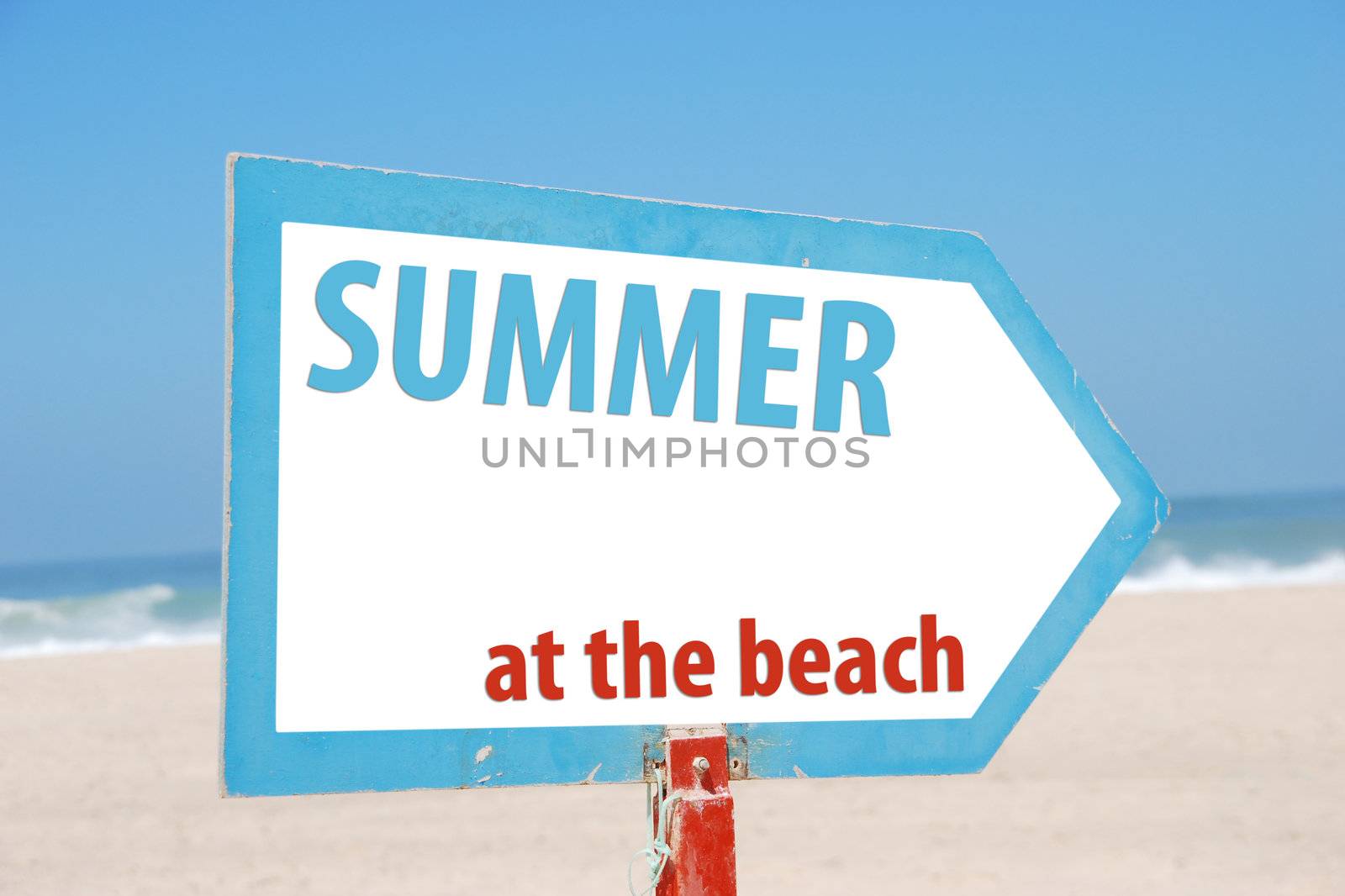 conceptual picture with summer at the beach sign against a blue sky and sandy beach