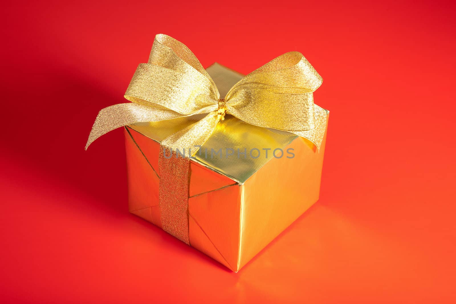 golden gift box with bow over red background
