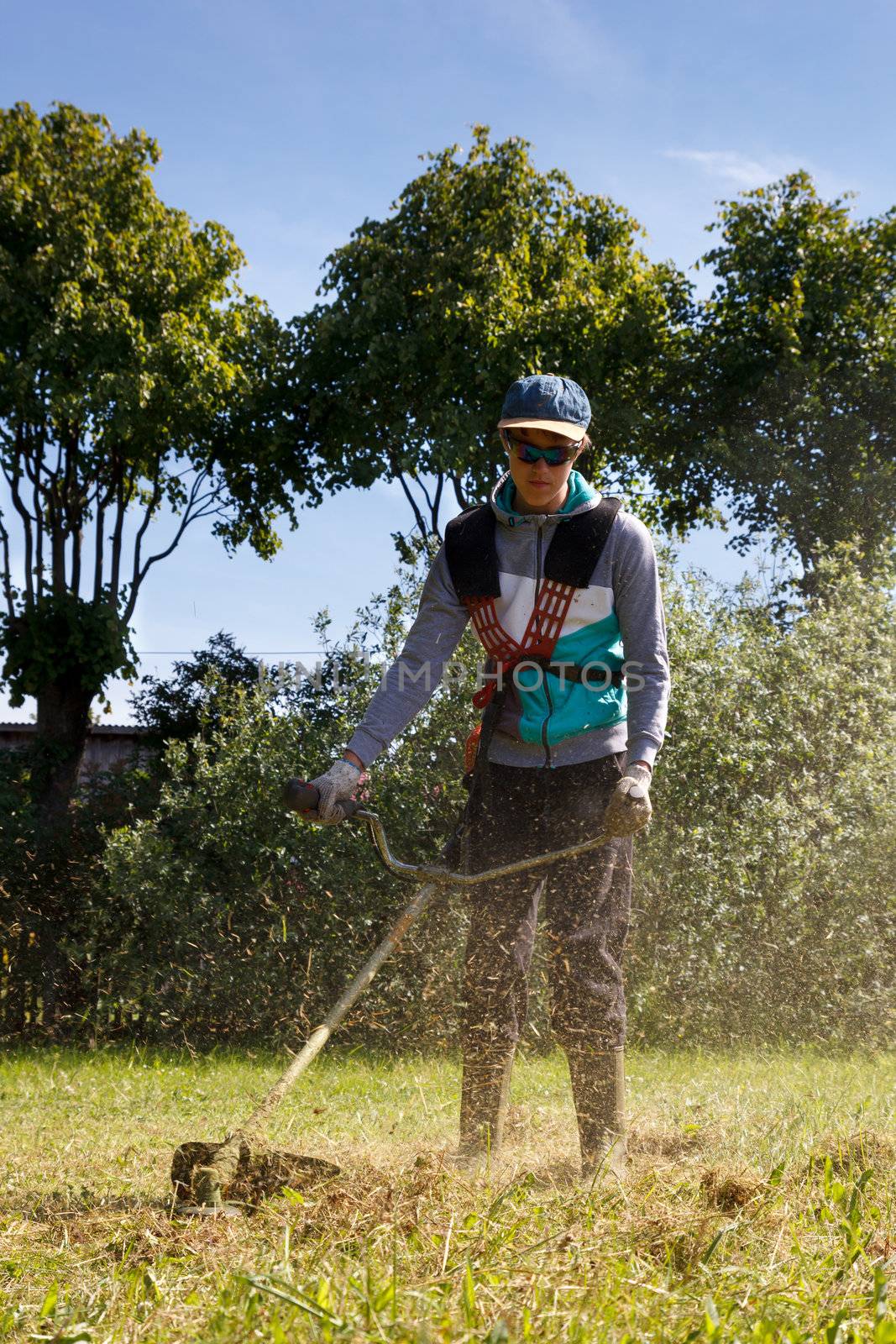 boy working on a trimmer in a sunny summer day