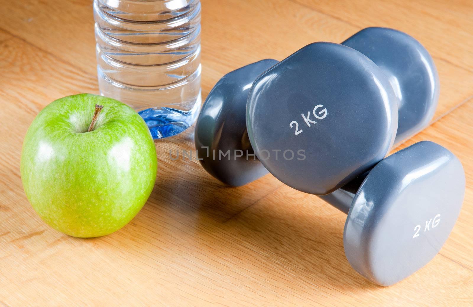 Pair of dumbbells, green apple, measuring tape and bottle of water. Exercise and healthy diet concept.