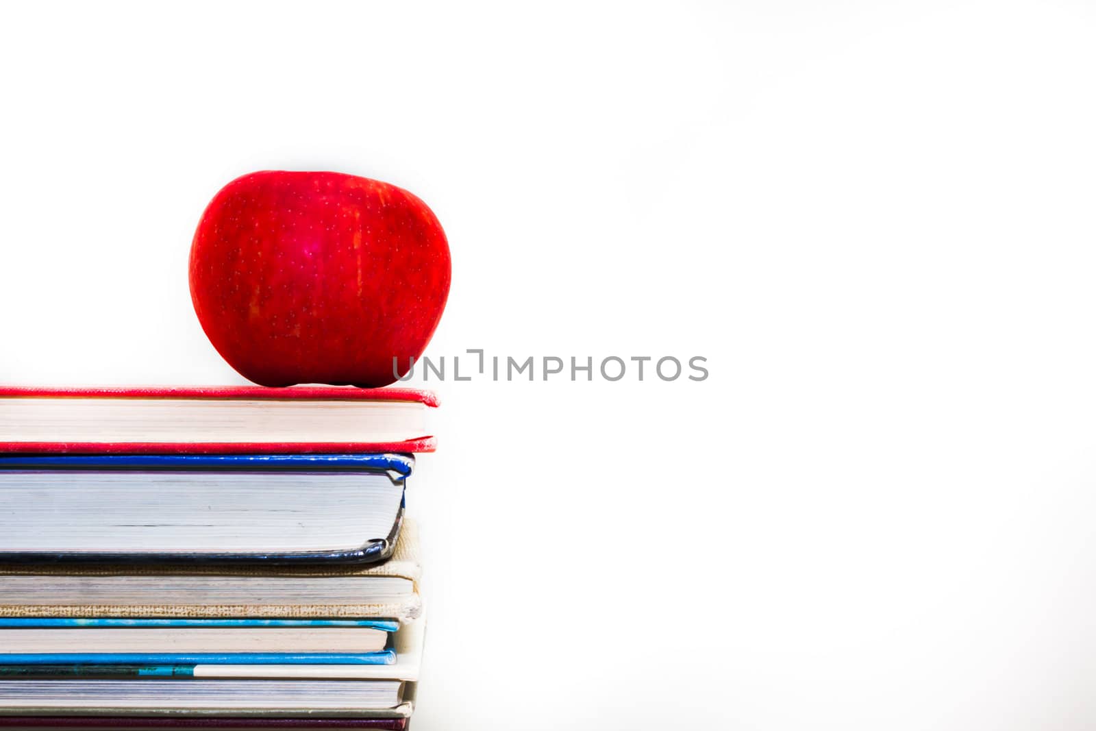 Stack of books with a single red apple on top