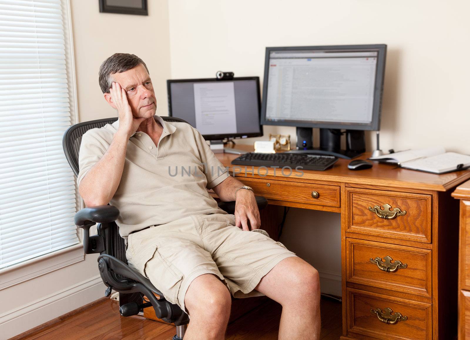 Senior male working in home office by steheap