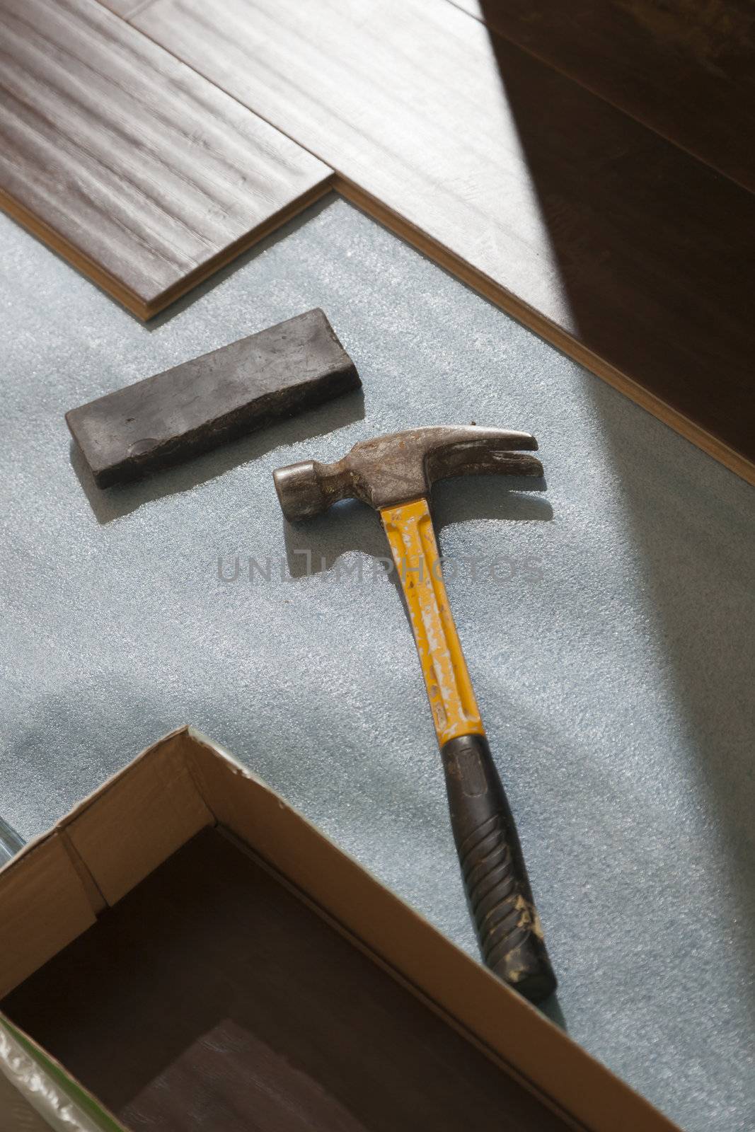 Hammer and Block with New Laminate Flooring Abstract.