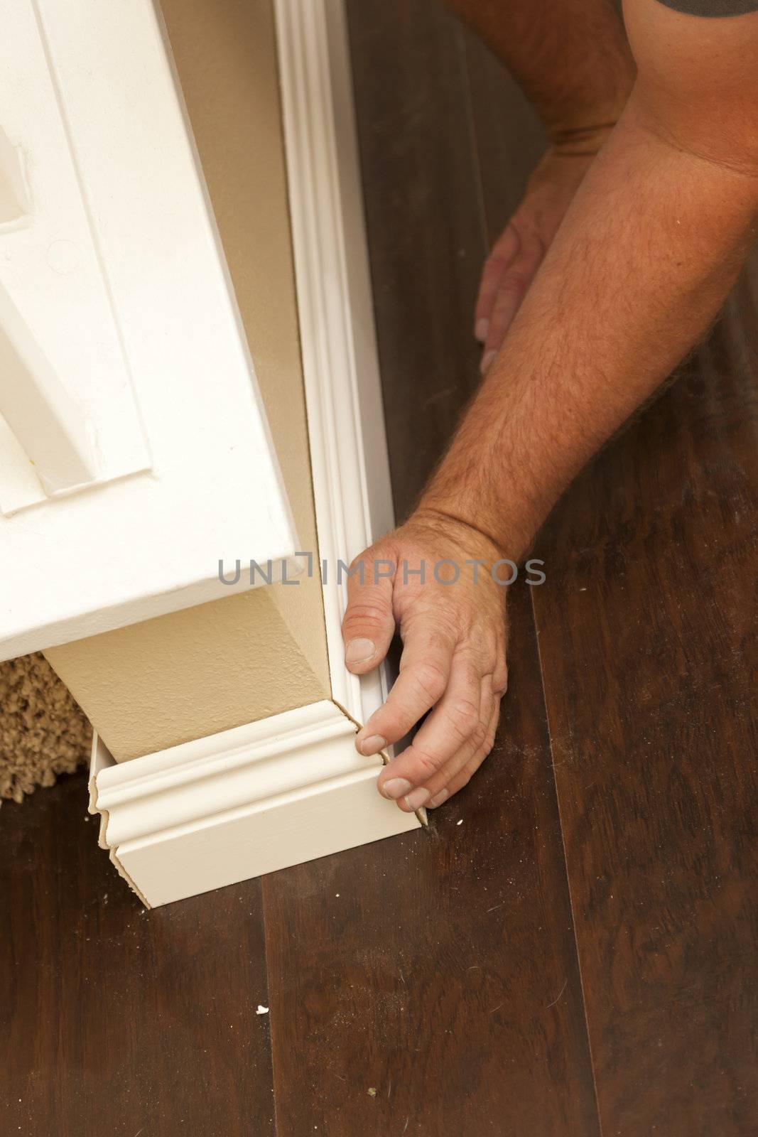 Contractor Fitting New Baseboard to Wall and New Laminate Flooring Abstract.