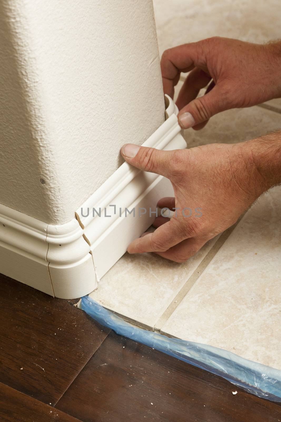 Contractor Installing New Baseboard with Bull Nose Corners and New Laminate Flooring Renovation Abstract.