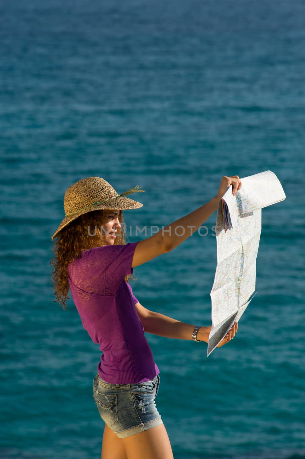 Woman looking at a map against the background of the ocean