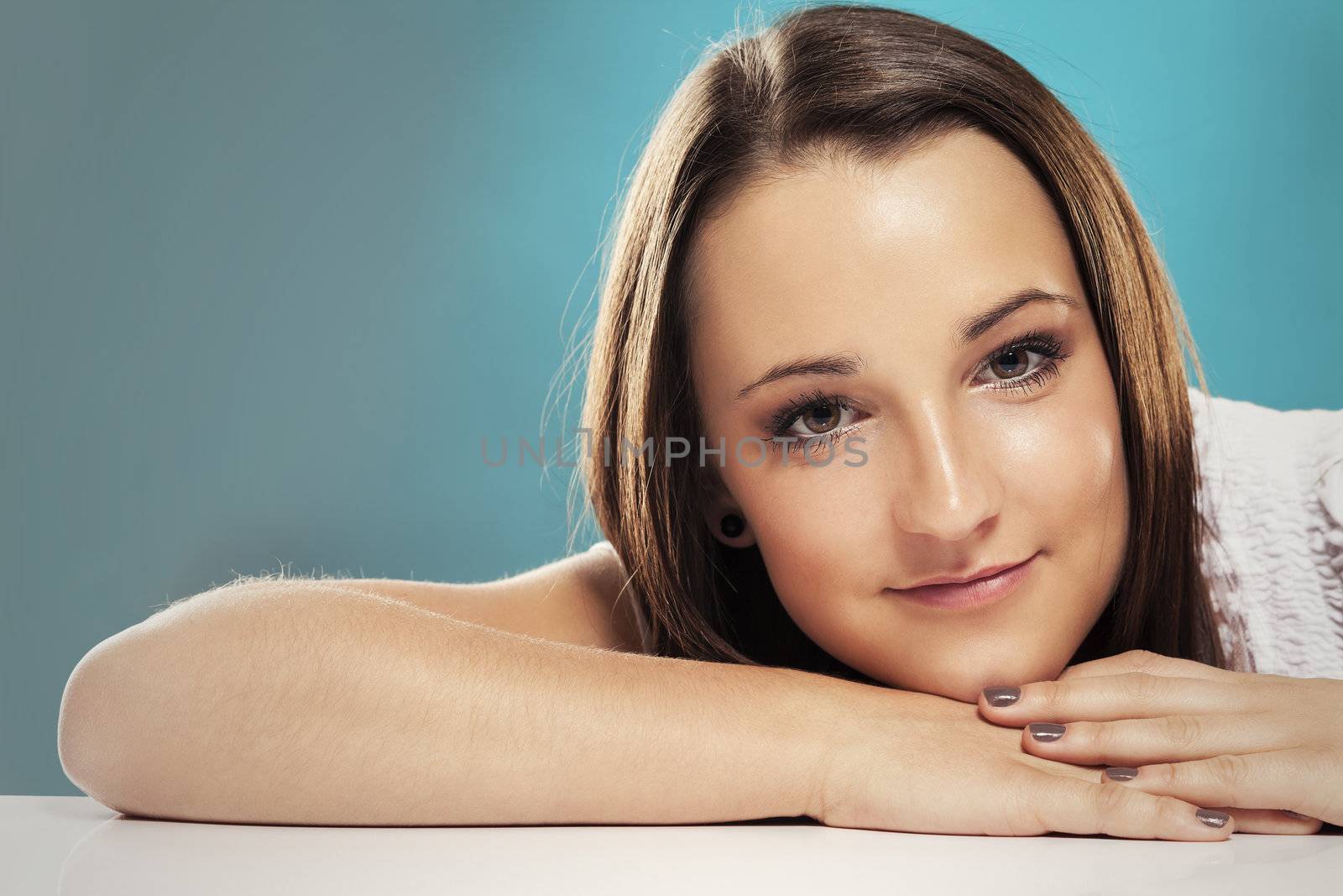 portrait of a teenager lying on a white table with green background