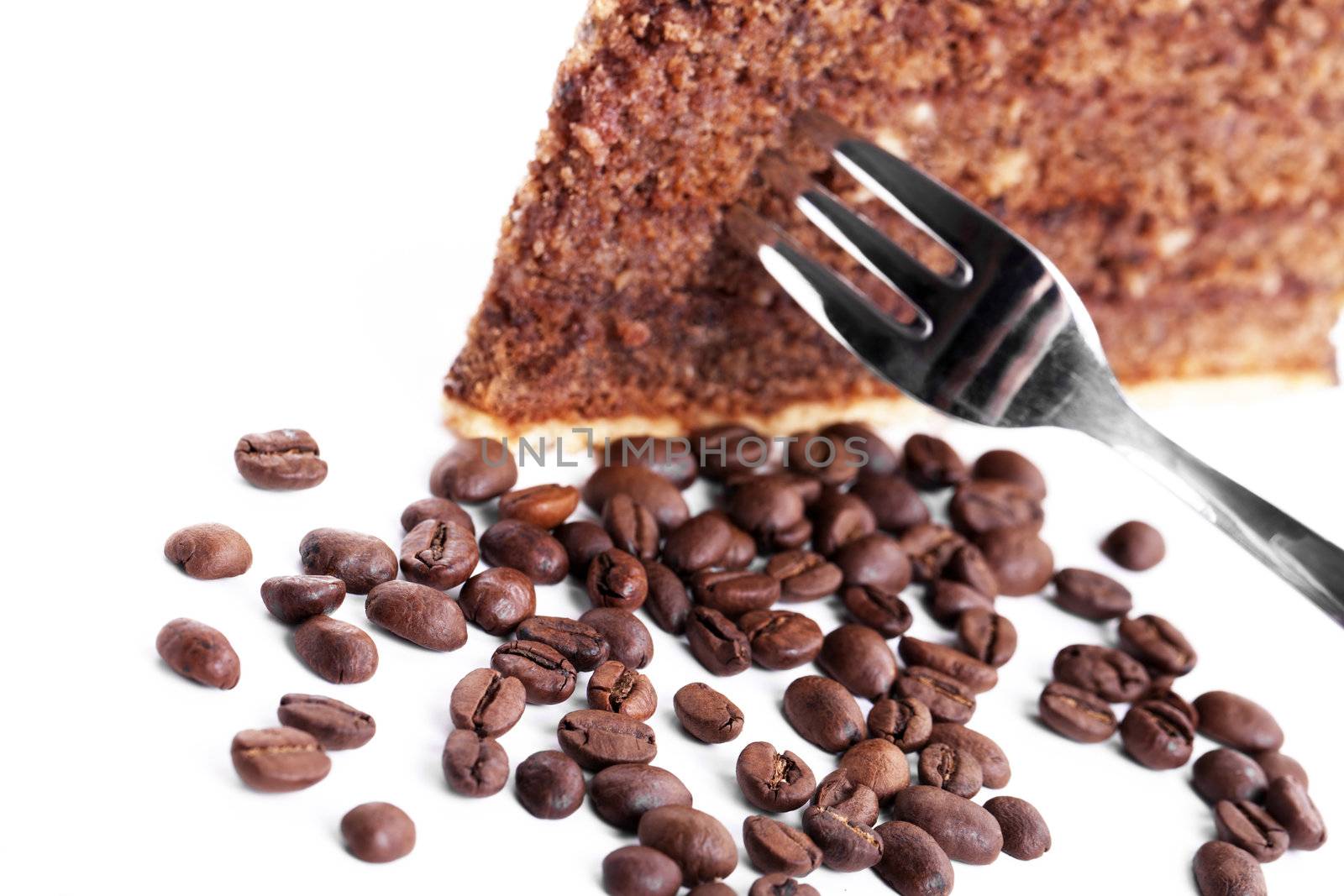 chocolate cake with a fork inside and coffee beans on white background