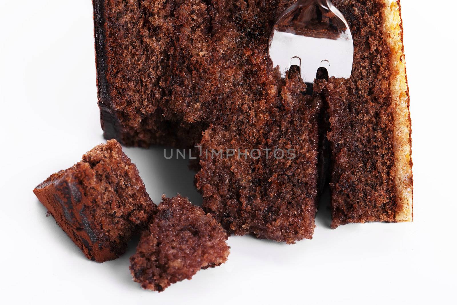 closeup of a fork in a broken chocolate cake on white background