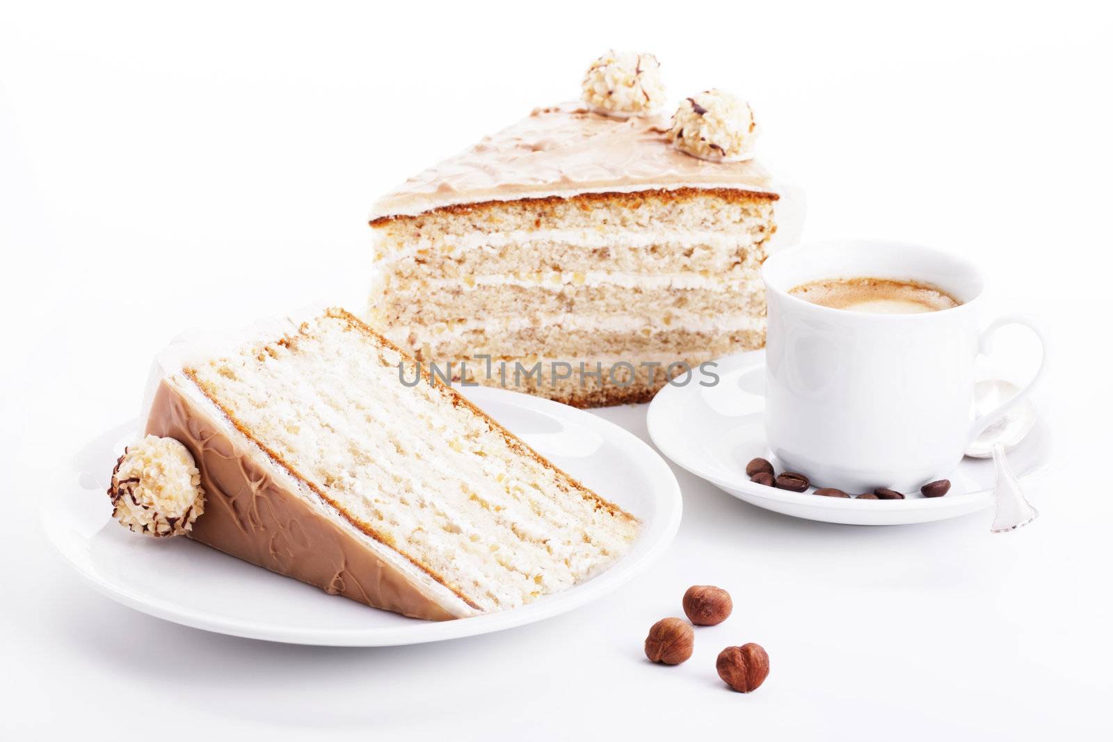 hazelnut cream cake with a cup of coffee and three hazelnuts on white background
