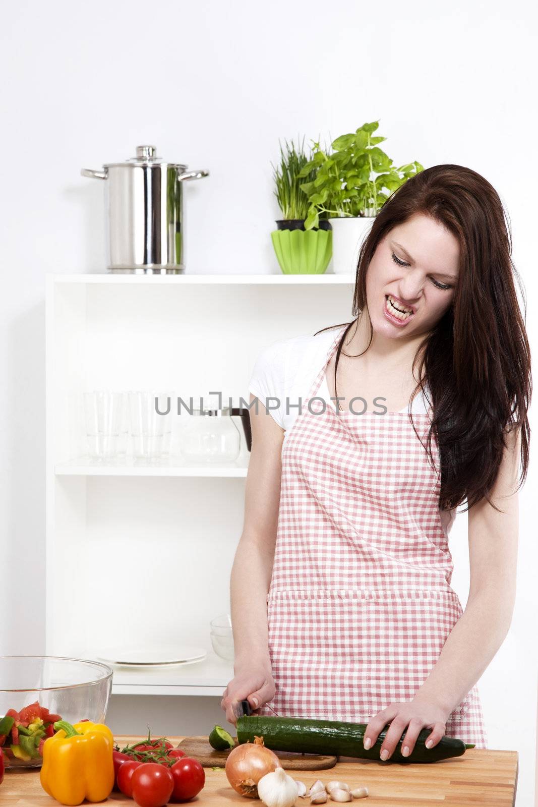 angry woman in a kitchen cutting a cucumber on a chopping board