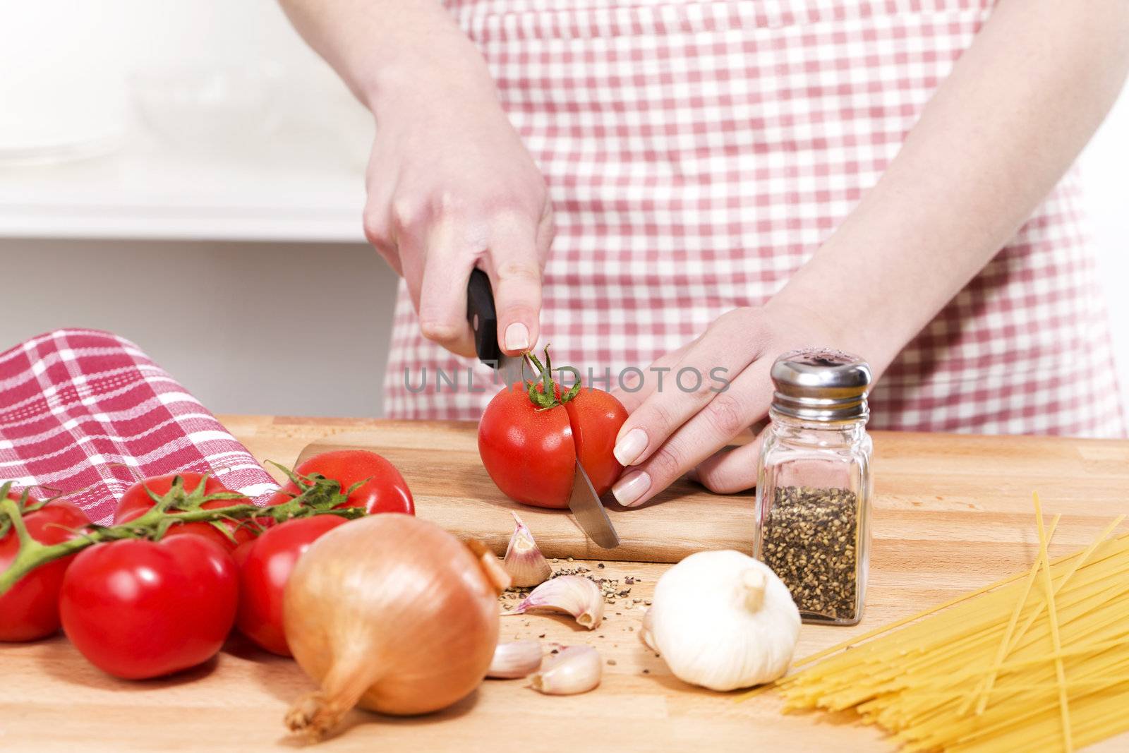 closeup of hands cutting tomatoes for spaghetti