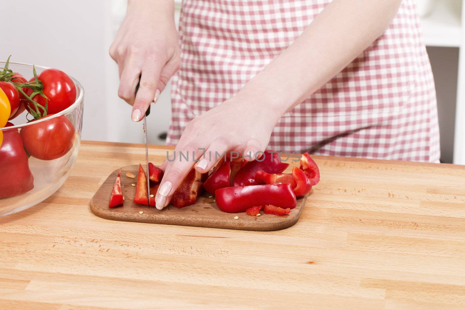 closeup of hands cutting red paprika on a chopping board