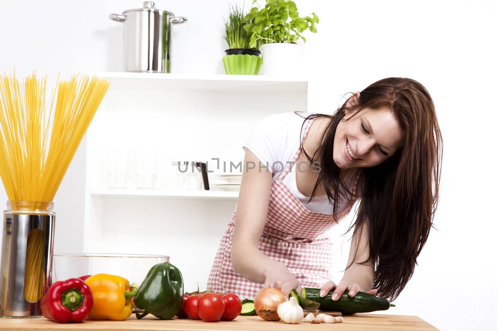 happy woman in kitchen chopping cucumber