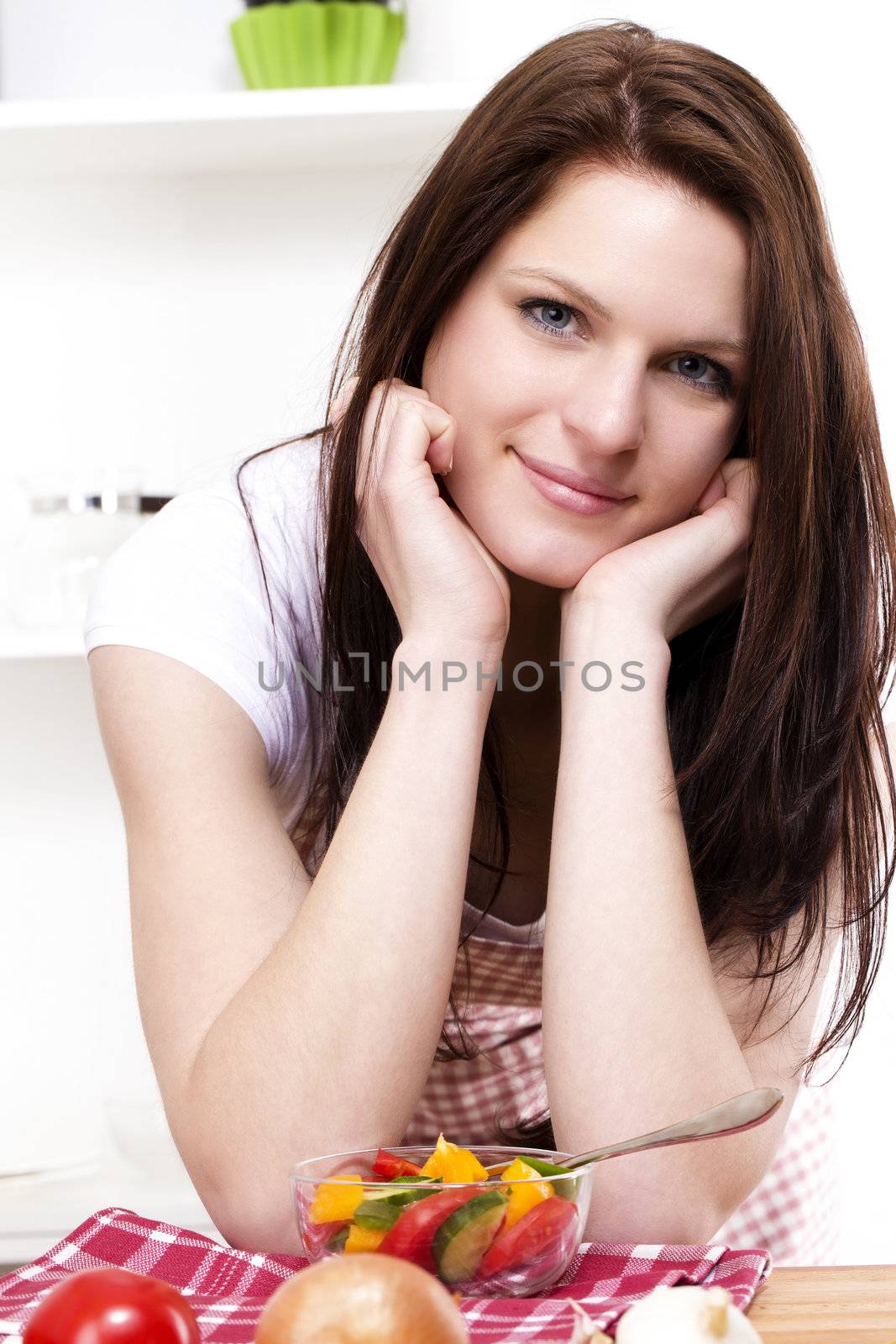 portrait of a smiling young woman in a kitchen with a salad