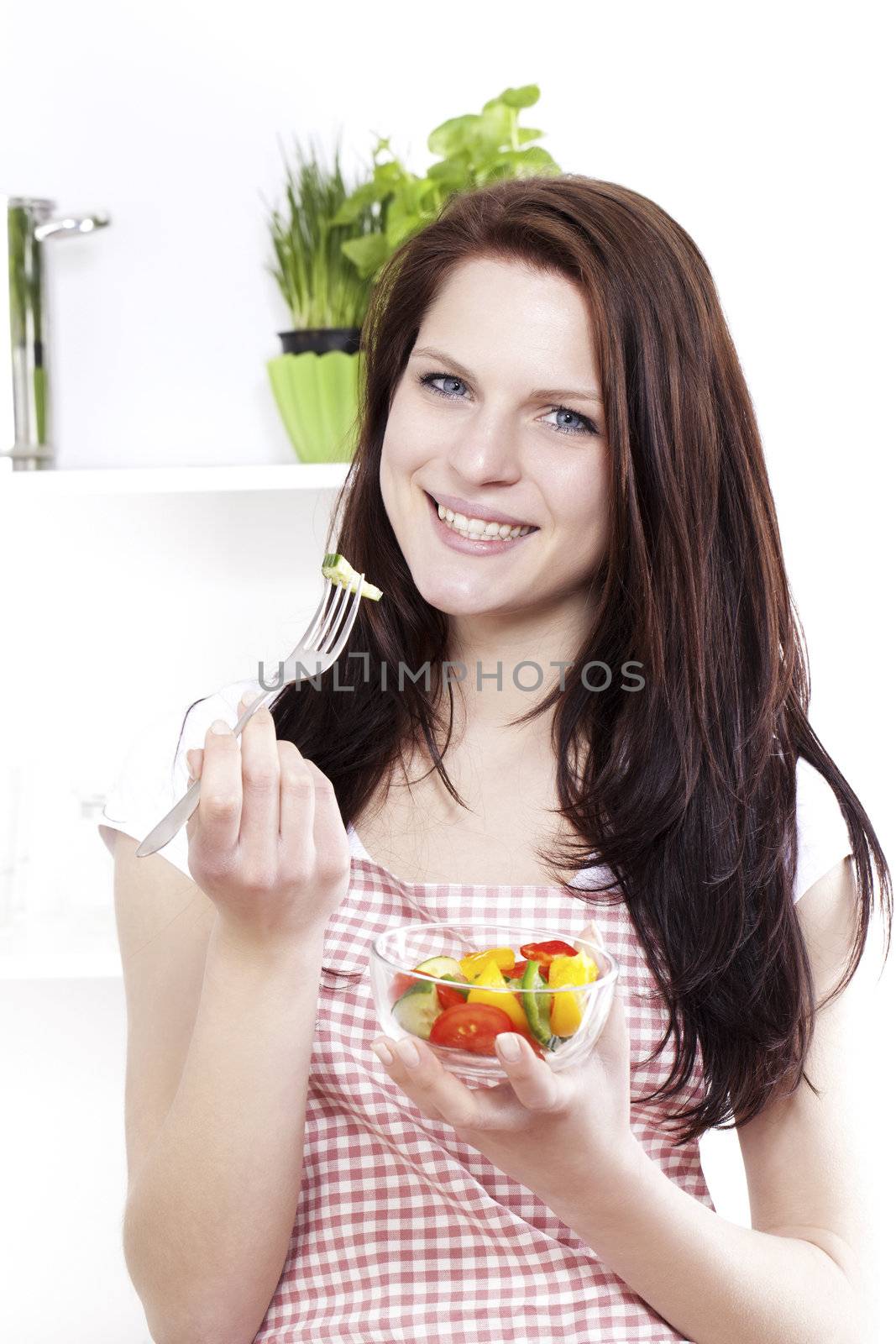 young happy woman in kitchen eating mixed salad