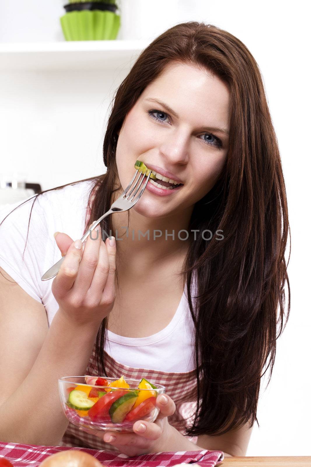 pretty woman in her kitchen eating mixed salad