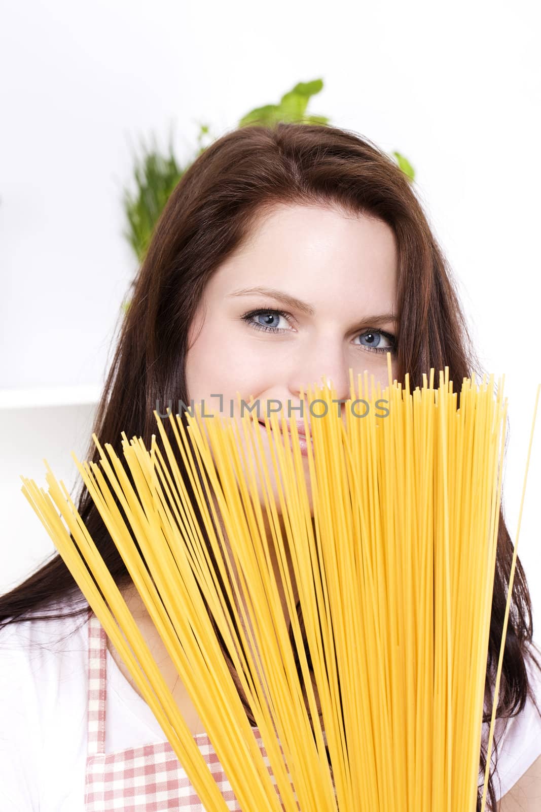 young pretty smiling woman is hiding behind some spaghetti